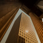 A low angle photo of a city scene with pillars and a skyscraper