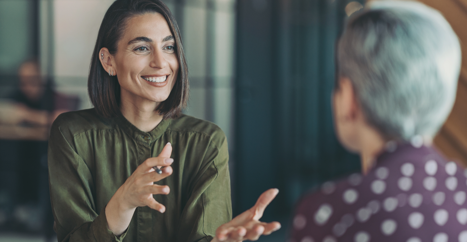 Two people engaged in conversation, one smiling broadly and gesturing with her hands.