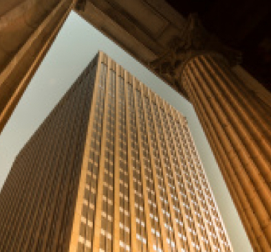 Low-angle view of a skyscraper framed by two large classical columns.