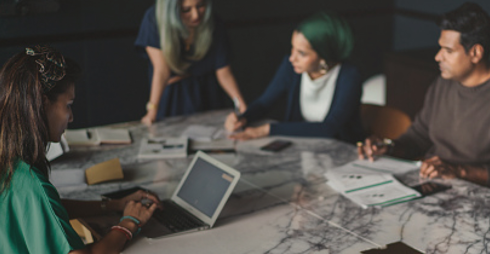 A group of diverse professionals work around a conference table