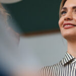 Smiling woman in a striped shirt with a blurred background.