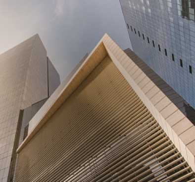 Low-angle view of three modern skyscrapers with reflective glass and horizontal louvers on the facade.