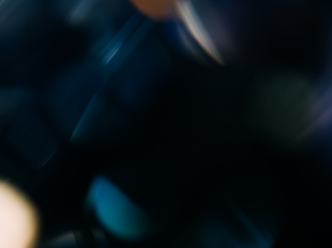 Abstract image with blurred dark colors, including blue, green, and orange.