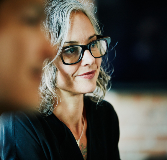 Close-up portrait of a woman with gray hair and black glasses.