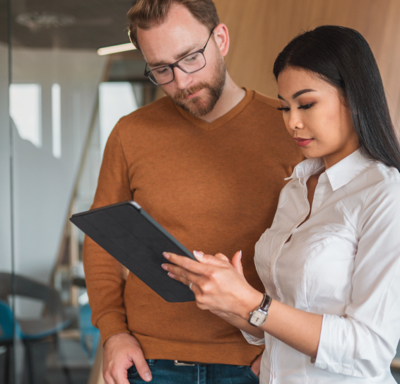 A man and woman looking at a tablet in an office setting.