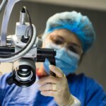 A healthcare worker adjusts a surgical microscope in a medical setting.