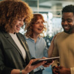 Three people smiling and standing close together indoors.