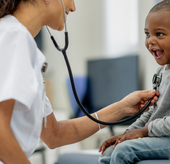 Healthcare professional using a stethoscope on a smiling child.