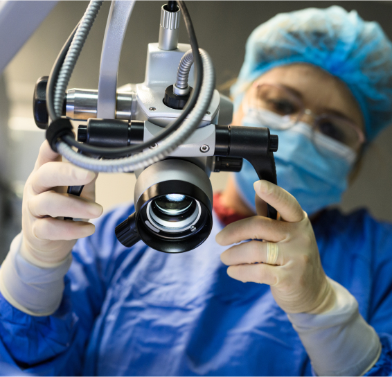 A healthcare worker adjusts a surgical microscope in a medical setting.