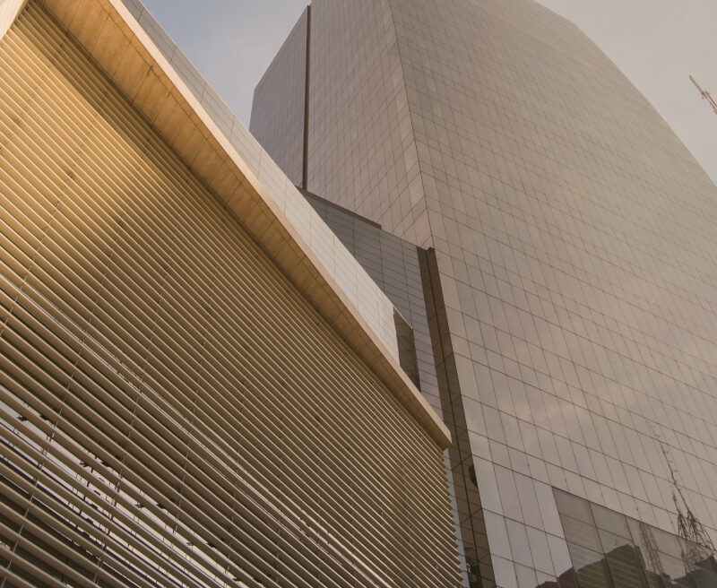 Low-angle view of modern skyscrapers in Latin America with louvered and glass facades under a clear sky.