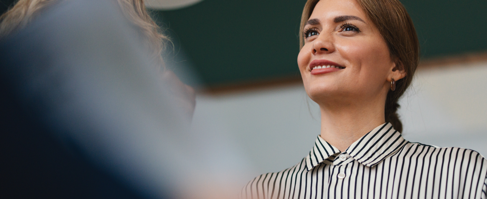 A woman smiling, wearing a striped shirt.