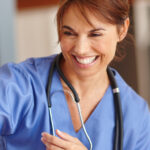 Smiling woman in blue scrubs with a stethoscope around her neck.