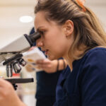 Young woman using a microscope in a laboratory setting.