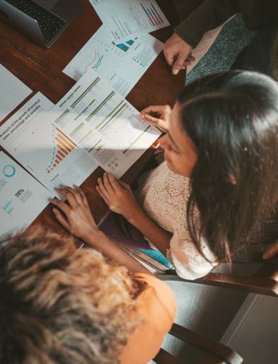 Group of people reviewing charts and graphs on a wooden table.