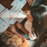 People examining printed charts and graphs at a table.