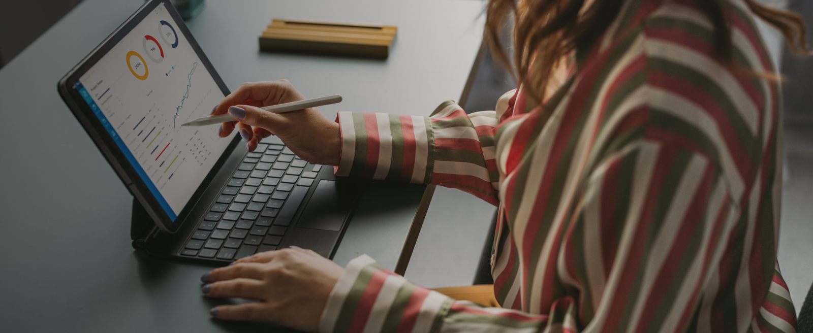 Person using a stylus on a laptop screen at a desk.