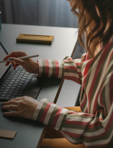 Person using a stylus on a laptop screen at a desk.