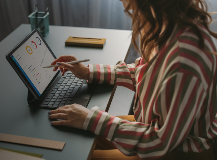 A person using a stylus on a tablet with a data dashboard.