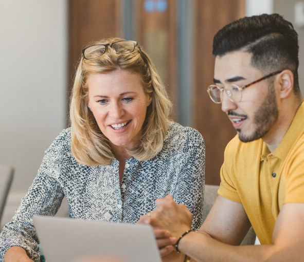 A man and a woman work together on a laptop