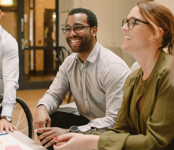 A man and a woman smiling at their coworkers out of frame