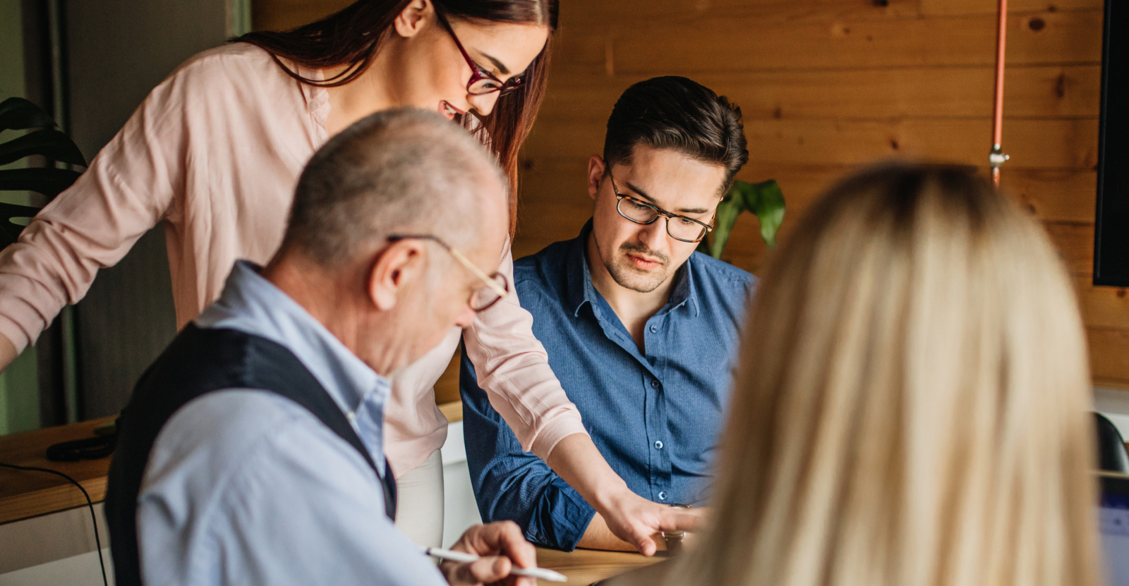 A group of four people engaging in a discussion at a table in an office setting.