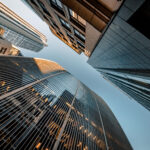 Upward view of several modern skyscrapers with clear blue sky in between.