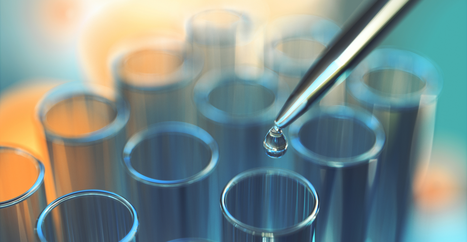 Close-up of test tubes with a pipette holding a droplet above them.