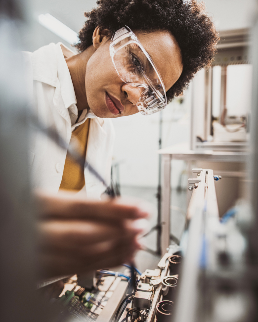 A woman in a lab wearing safety glasses performs an experiment