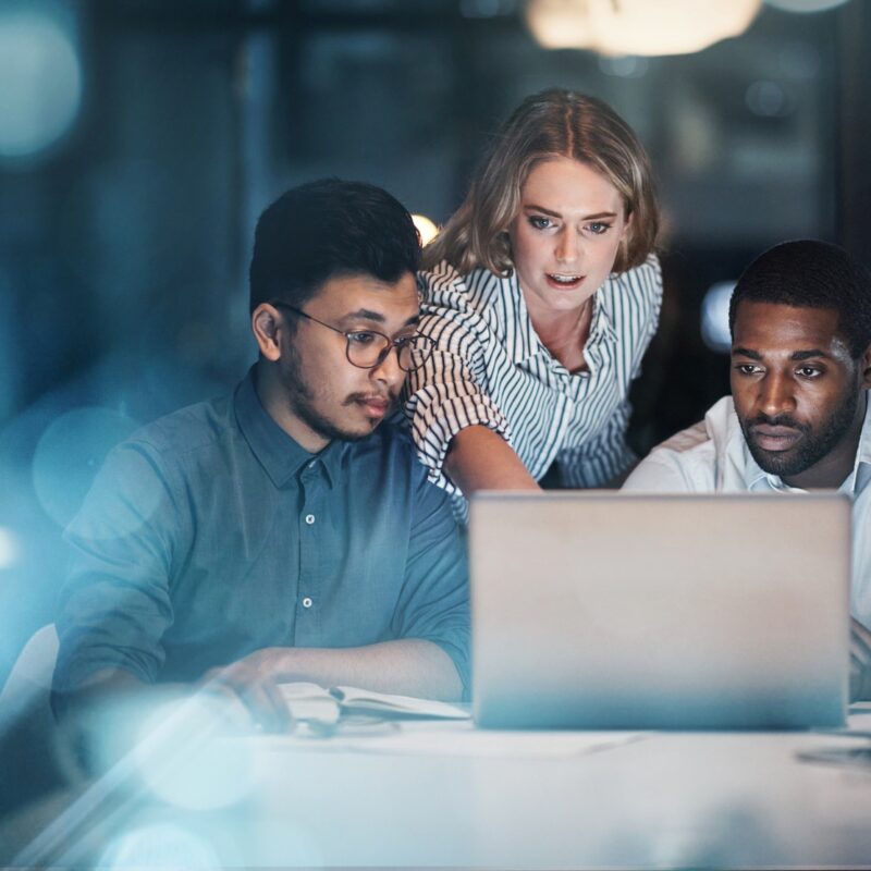 three people working together in front of a laptop computer