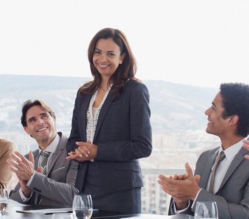 Co-workers clapping for businesswoman in conference room