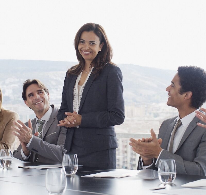 Co-workers clapping for businesswoman in conference room