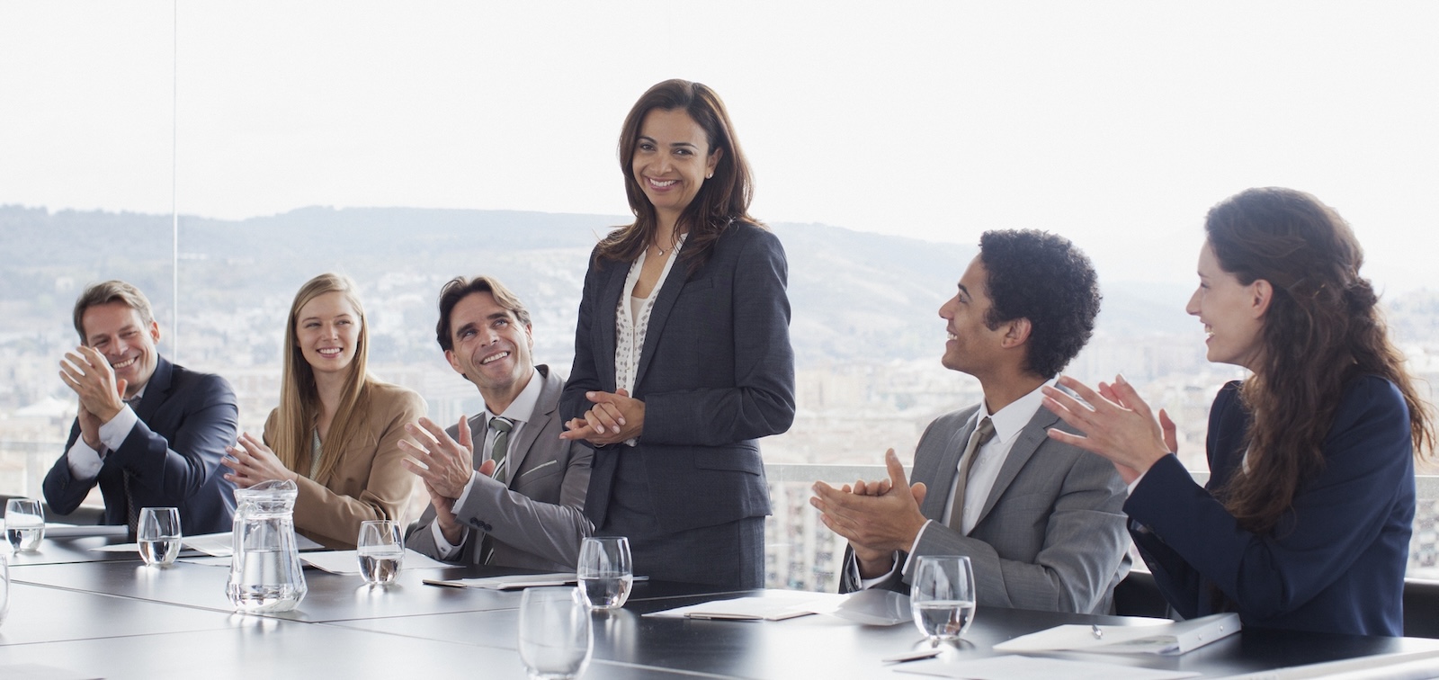 Co-workers clapping for businesswoman in conference room