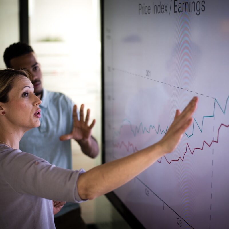 Businesswoman explaining graph to her coworker in conference room.