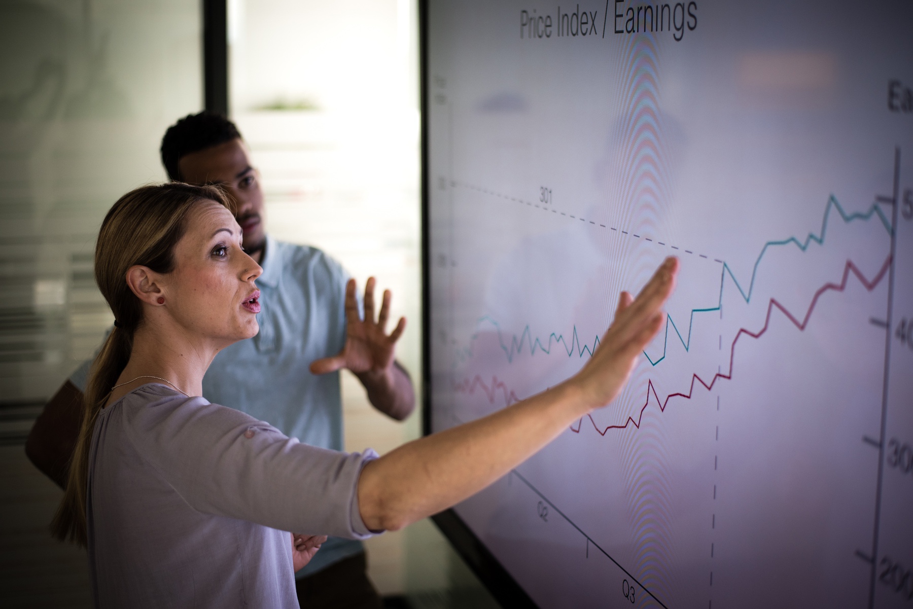 Businesswoman explaining graph to her coworker in conference room.