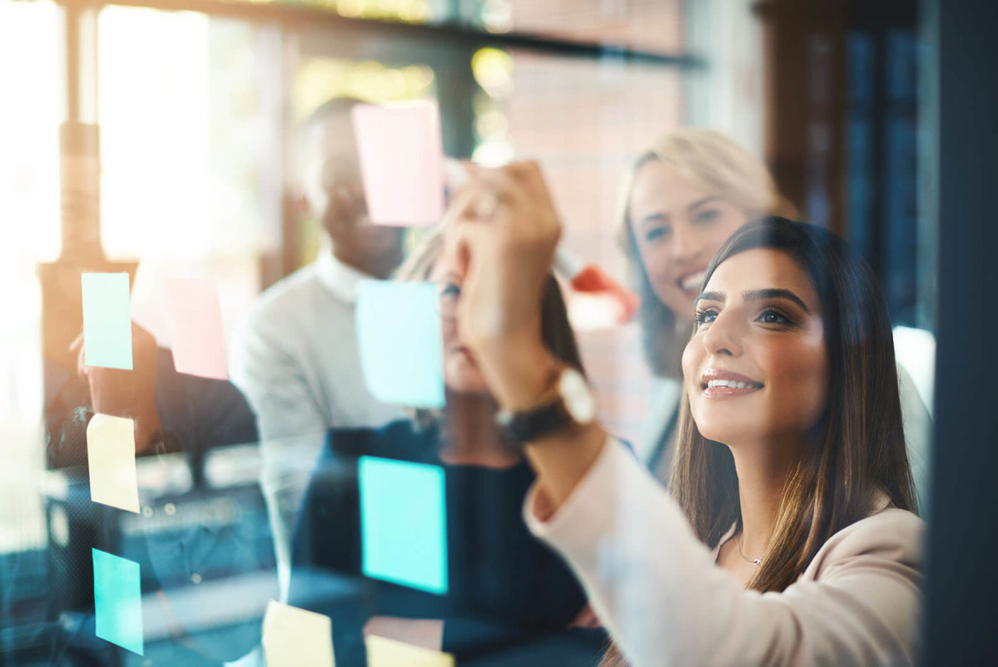 Smiling women writing on a glass wall